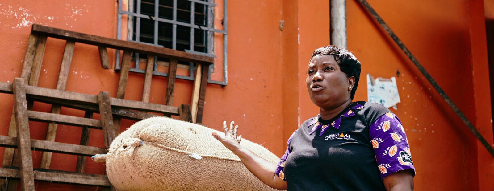 Doumbia Assata Kone steht vor Säcken mit Kakaobohnen.
